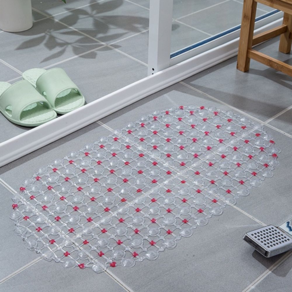 Transparent bath mat with red accents on a bathroom floor.