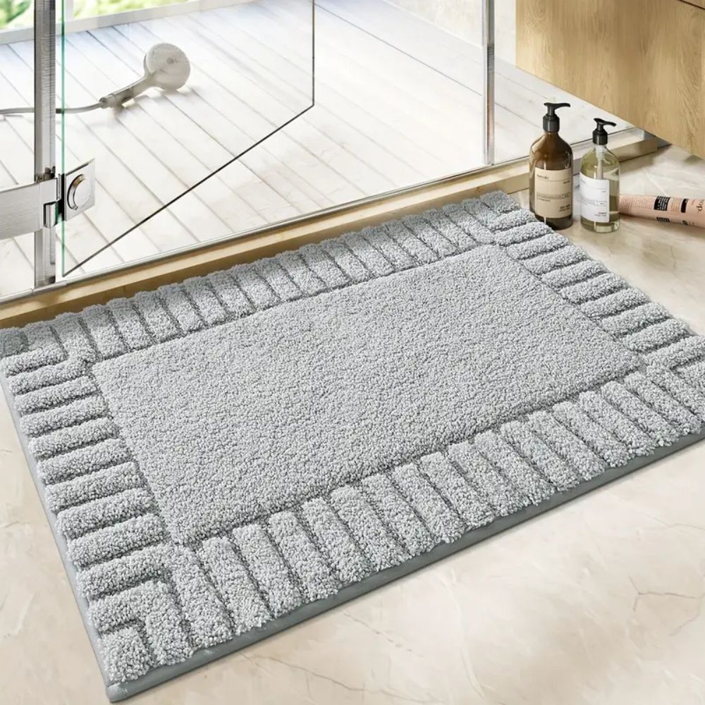 Gray doormat with textured pattern on a light wooden floor.