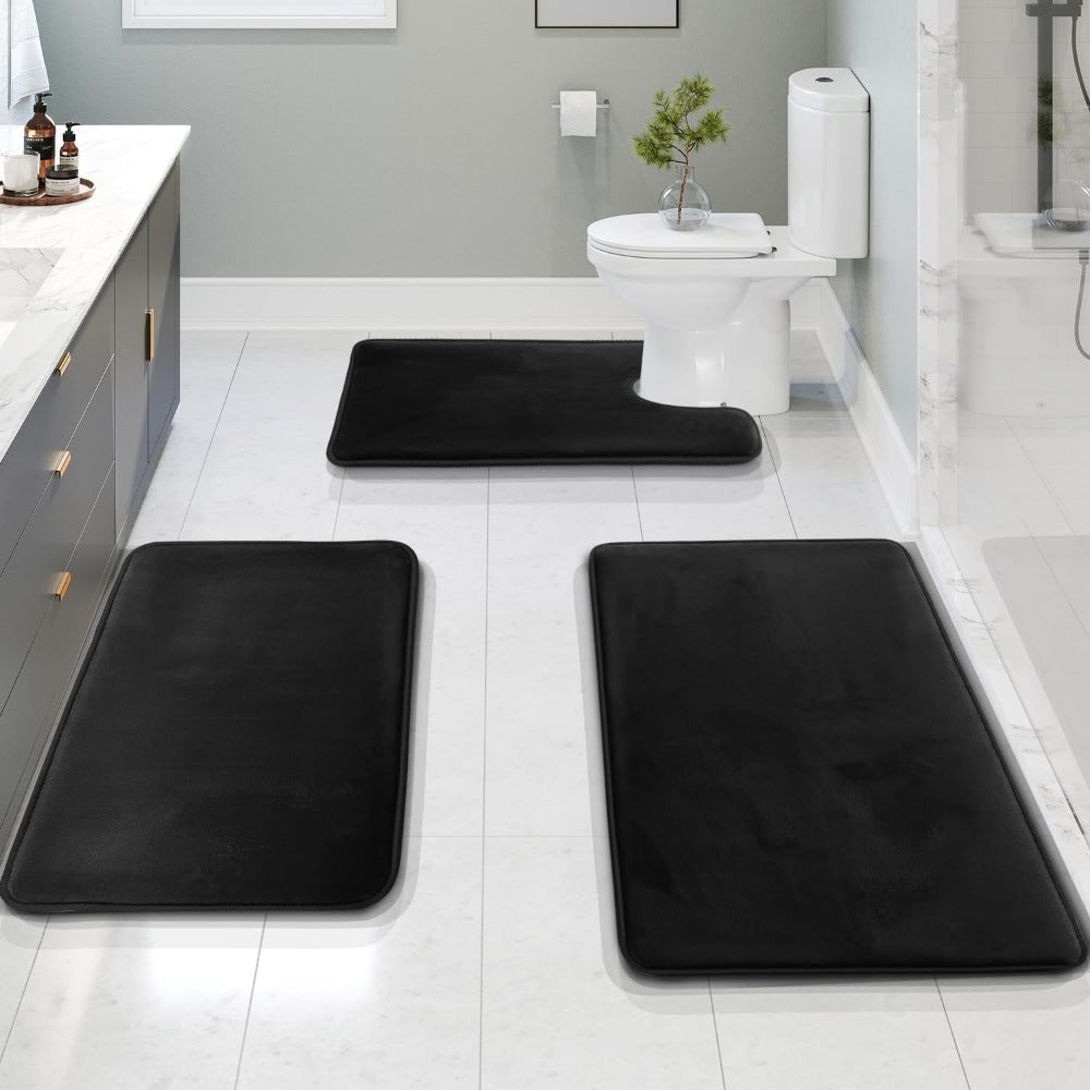 Black bath mats on a bathroom floor with a toilet and sink in the background.