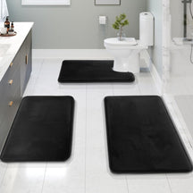 Black bath mats on a bathroom floor with a toilet and sink in the background.
