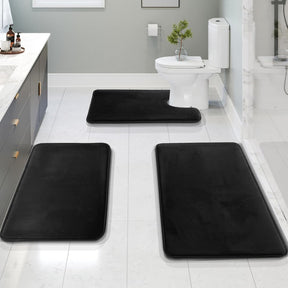 Black bath mats on a bathroom floor with a toilet and sink in the background.