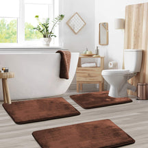 Bathroom with brown bath mats on the floor, white bathtub, and toilet.