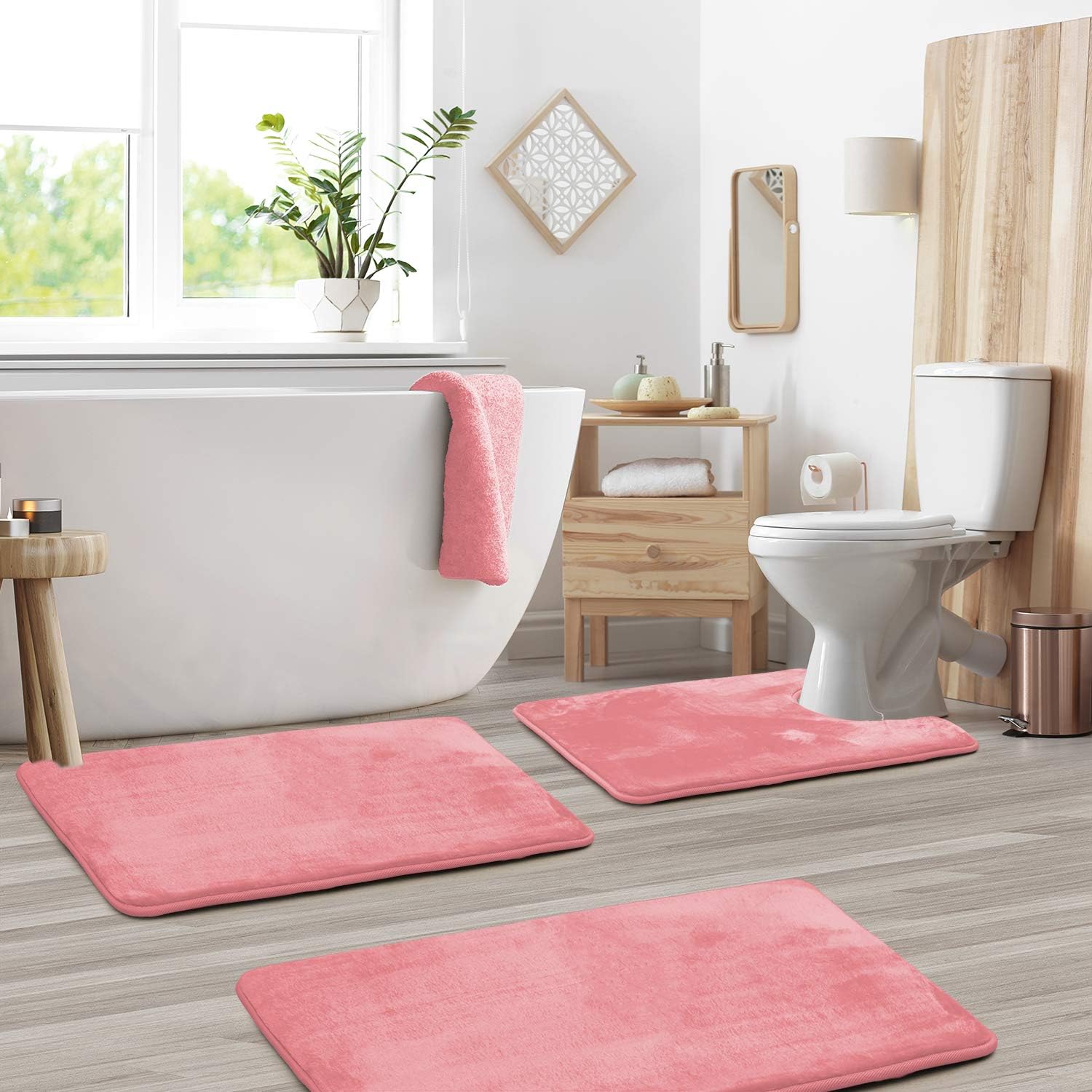Bathroom with pink bath mats on the floor, white bathtub, and toilet.
