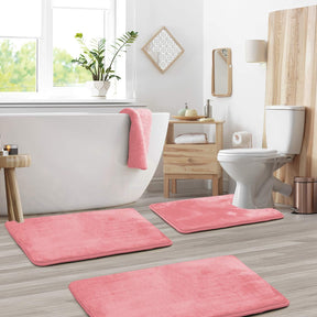 Bathroom with pink bath mats on the floor, white bathtub, and toilet.