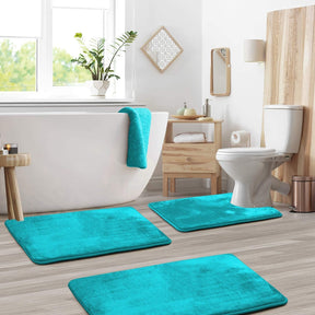 Bathroom with teal bath mats on the floor, white toilet, and wooden cabinet.