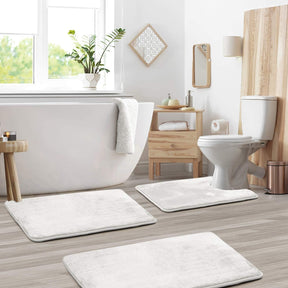 Bathroom with white bath mats on wooden floor, toilet, and bathtub.