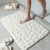 White textured bath mat on a bathroom floor with a person stepping onto it.