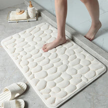 White textured bath mat on a bathroom floor with a person stepping onto it.