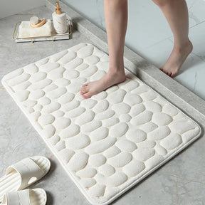 White textured bath mat on a bathroom floor with a person stepping onto it.