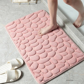 Pink textured bath mat on a bathroom floor with a child's feet stepping onto it.