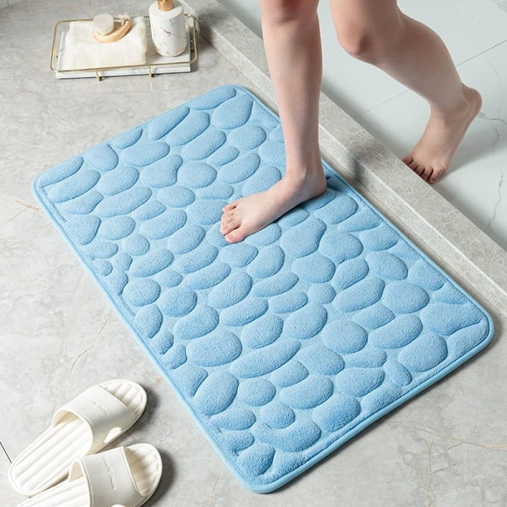 Blue textured bath mat on a bathroom floor with a child stepping onto it.
