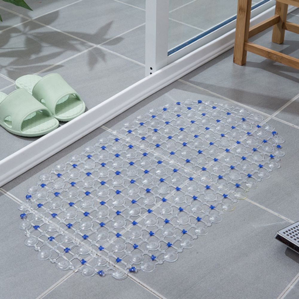 Clear bath mat with blue dots on a tiled bathroom floor