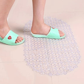 Clear rubber mat on a tiled floor with feet wearing light blue sandals stepping onto it.