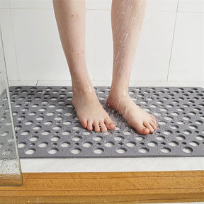 Person standing on a textured gray mat in a shower setting