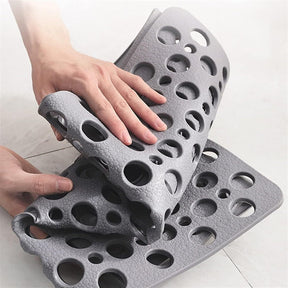 Gray silicone mat with unique texture being held by a hand on a light background