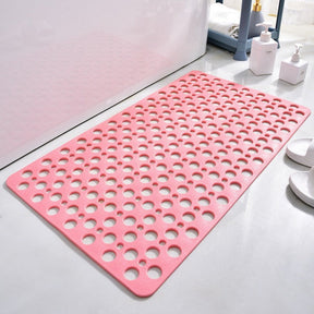 Pink bath mat with circular holes on a bathroom floor