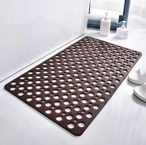 Brown bath mat with circular holes on a white bathroom floor