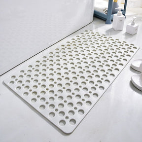 White bath mat with circular holes on a bathroom floor