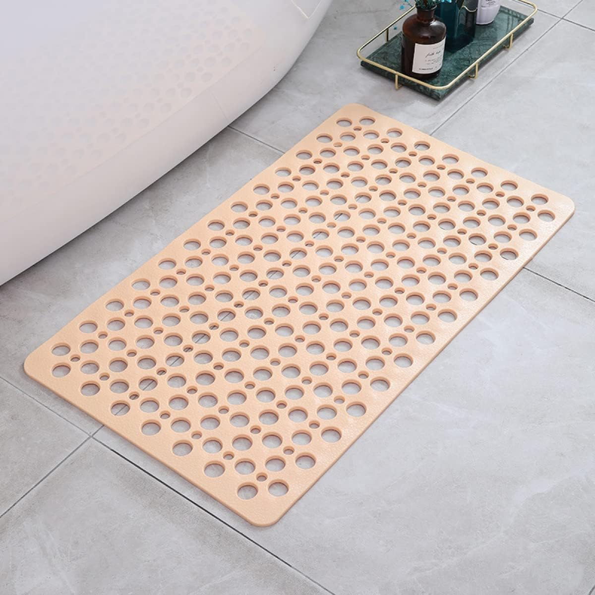 Beige bath mat with circular holes on a bathroom floor.