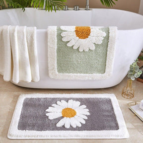 Bath mat with daisy design in front of a white bathtub