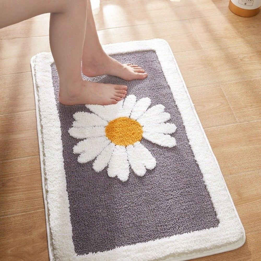 Gray bath mat with a daisy design on a wooden floor