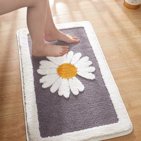 Gray bath mat with a daisy design on a wooden floor