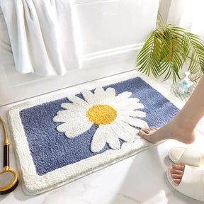 Bath mat with a daisy design on a bathroom floor.