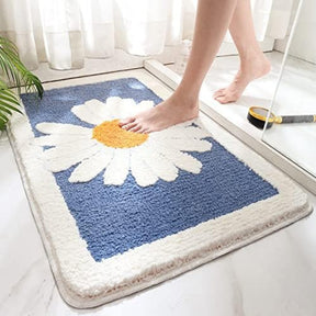 Blue bath mat with a white daisy design on a bathroom floor.