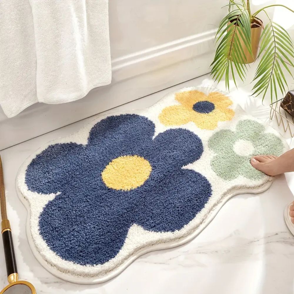 Floral-shaped bath mat with blue, yellow, and green flowers on a white floor.