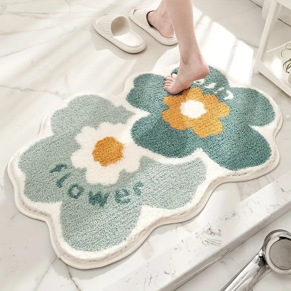 Floral-patterned bath mat with 'flowers' text on a bathroom floor.
