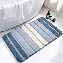 Striped bath mat on a bathroom floor with a bathtub and toiletries in the background.