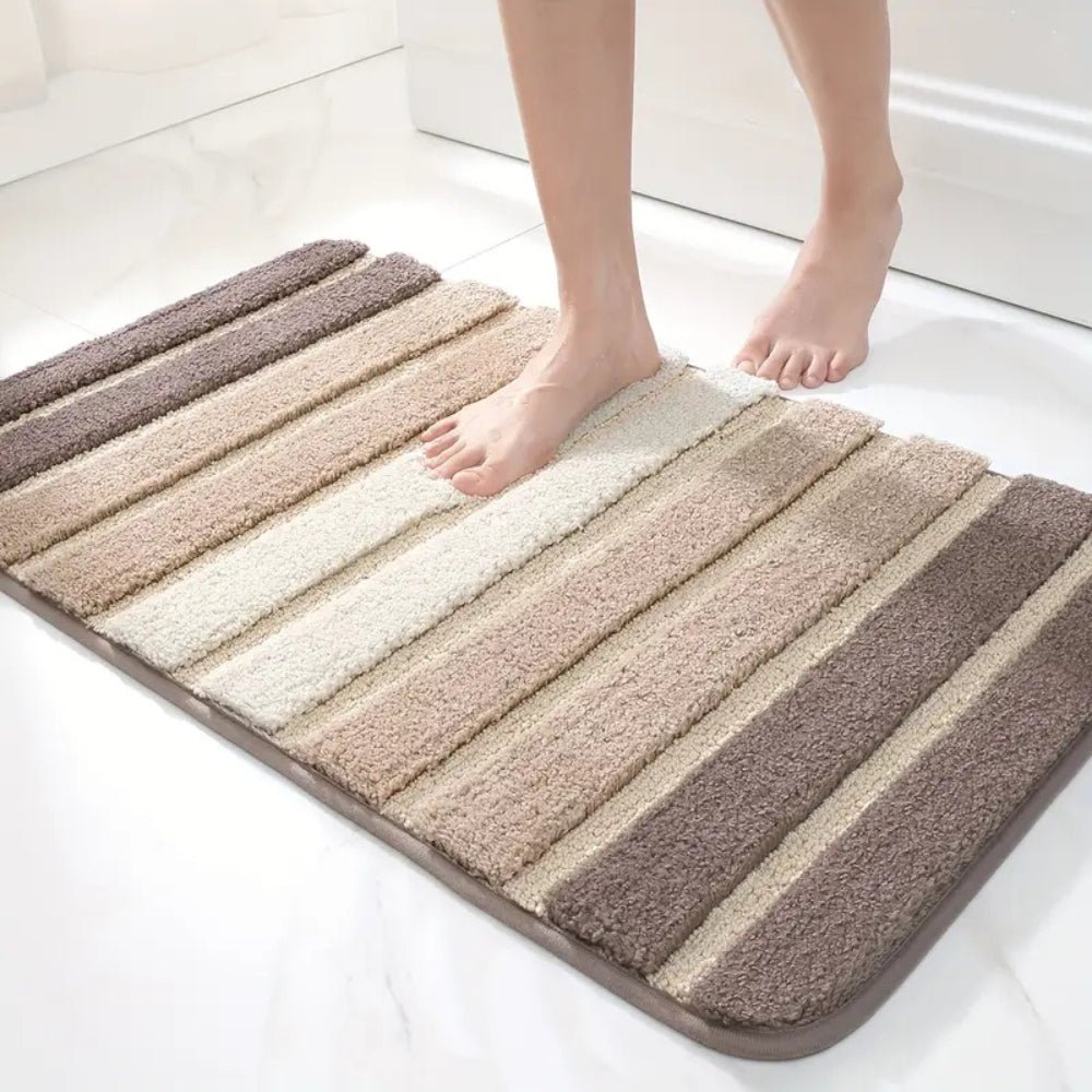 Striped bath mat with a person stepping onto it in a bathroom setting.