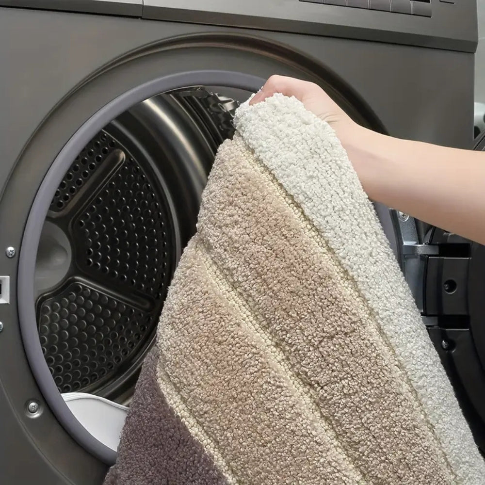 Person holding a textured towel in front of an open washing machine.
