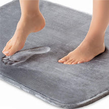 Person stepping onto a gray bath mat with water droplets.