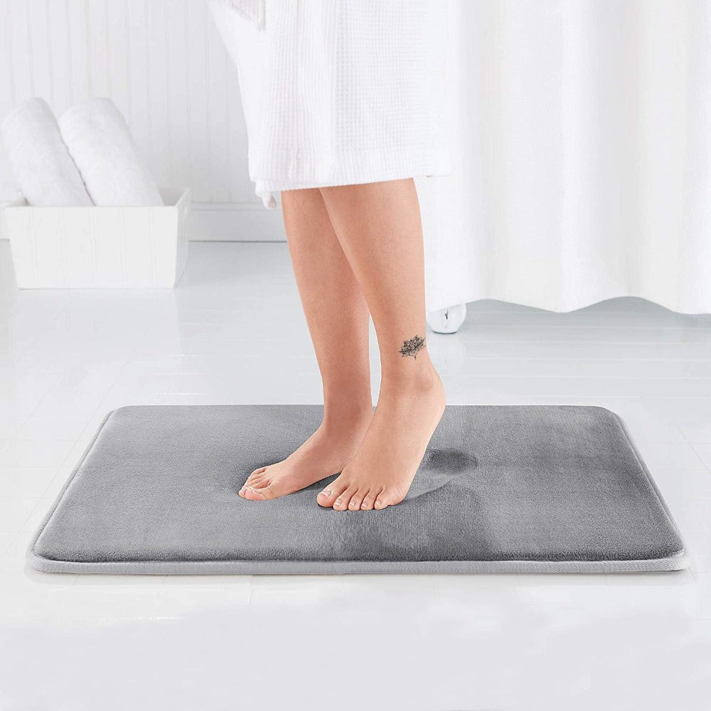 Person standing on a gray bath mat in a bathroom setting