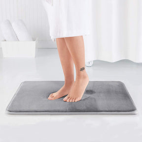 Person standing on a gray bath mat in a bathroom setting