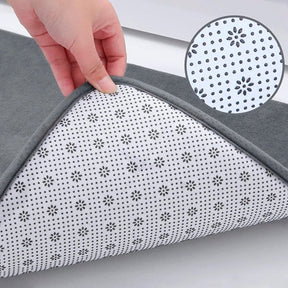 Gray and white patterned mat with a hand touching it on a light gray background