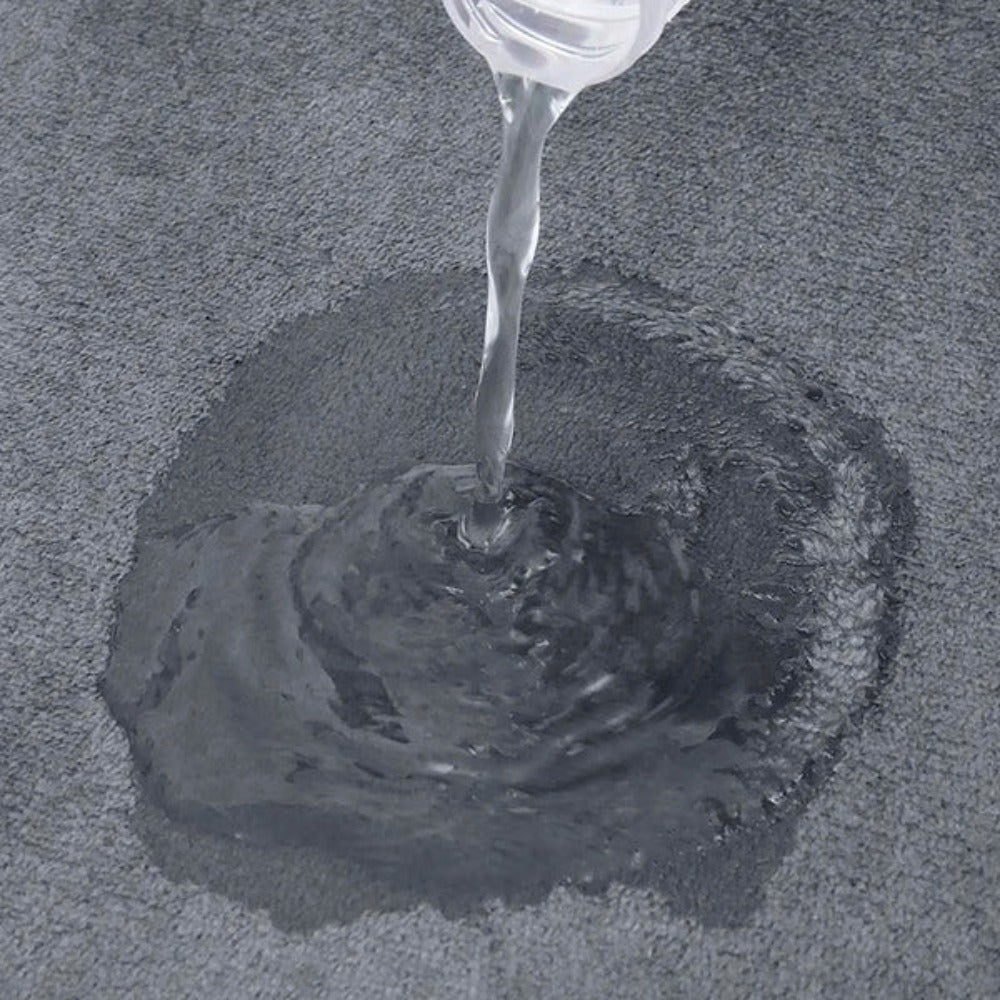 Clear liquid being poured onto a textured gray surface