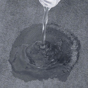 Clear liquid being poured onto a textured gray surface