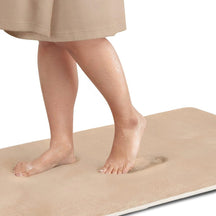 Person standing on a beige mat with a plain background