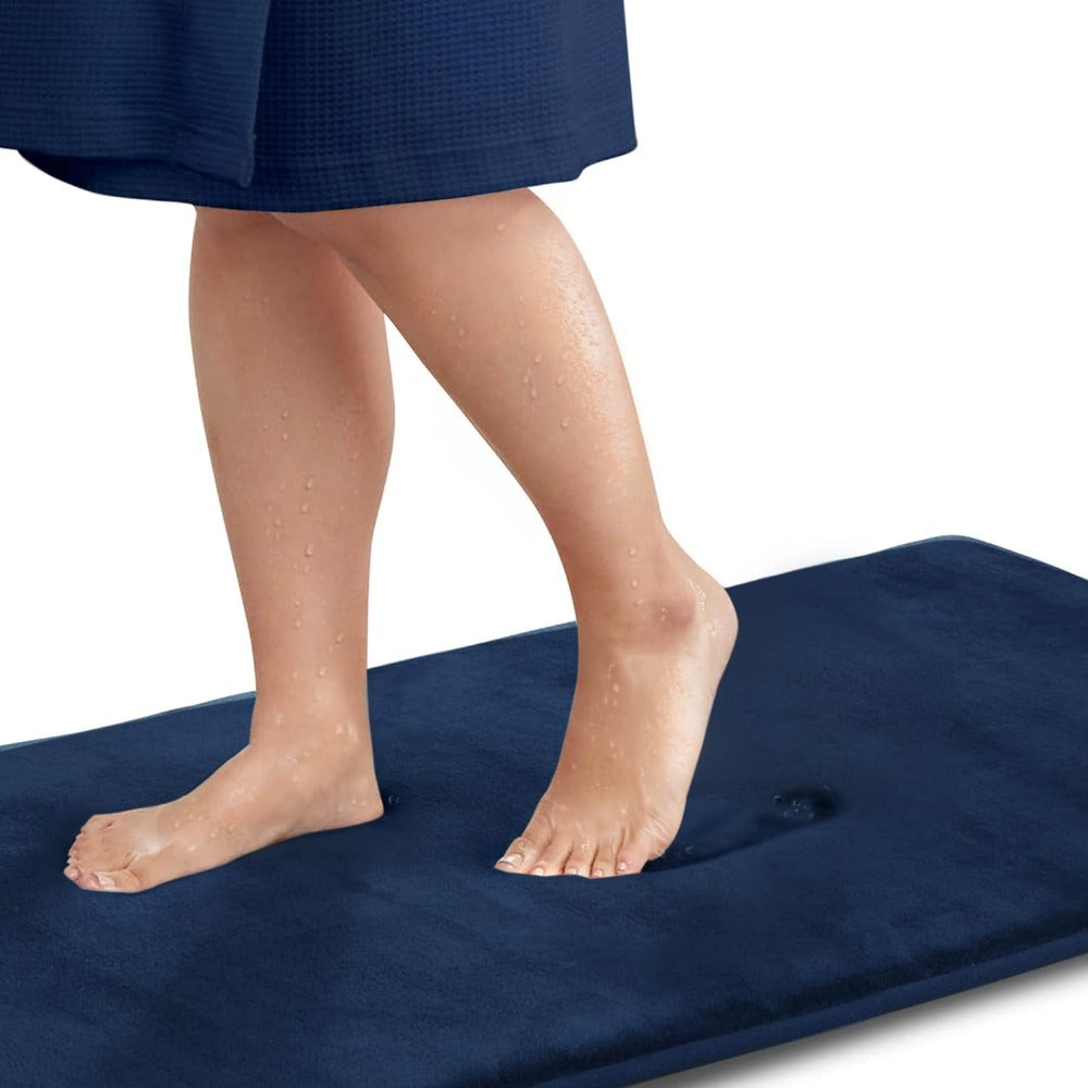 Person standing on a navy blue bath mat with a white background