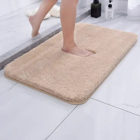 Beige bath mat on a bathroom floor with a person stepping onto it.
