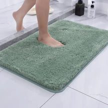 Green bath mat on a bathroom floor with a person stepping onto it.