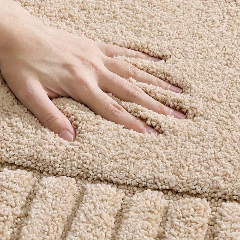 Hand touching a textured beige carpet