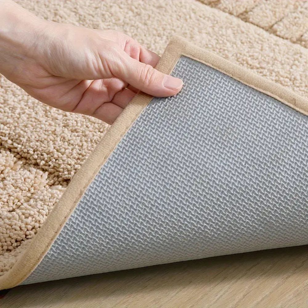 Hand holding a beige carpet pad with a gray underlay