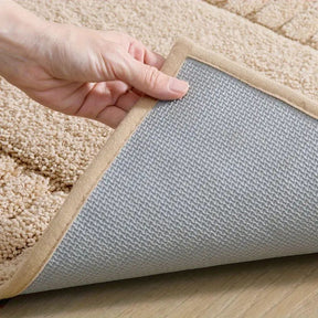 Hand holding a beige carpet pad with a gray underlay