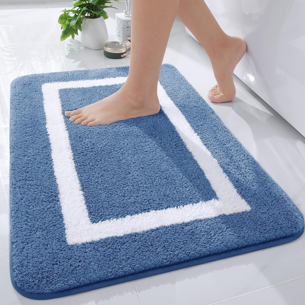 Blue bath mat with white border on a bathroom floor, person stepping onto it.