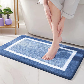 Person stepping onto a blue bath mat with white border in a bathroom setting.