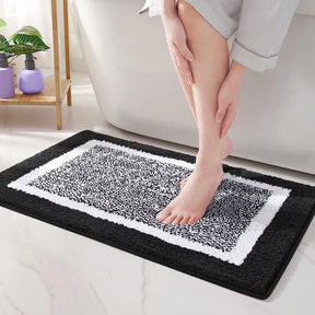 Person stepping onto a black and white patterned bath mat in a bathroom setting.