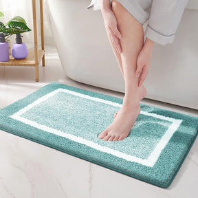 Person stepping onto a teal bath mat with a white border in a bathroom setting.